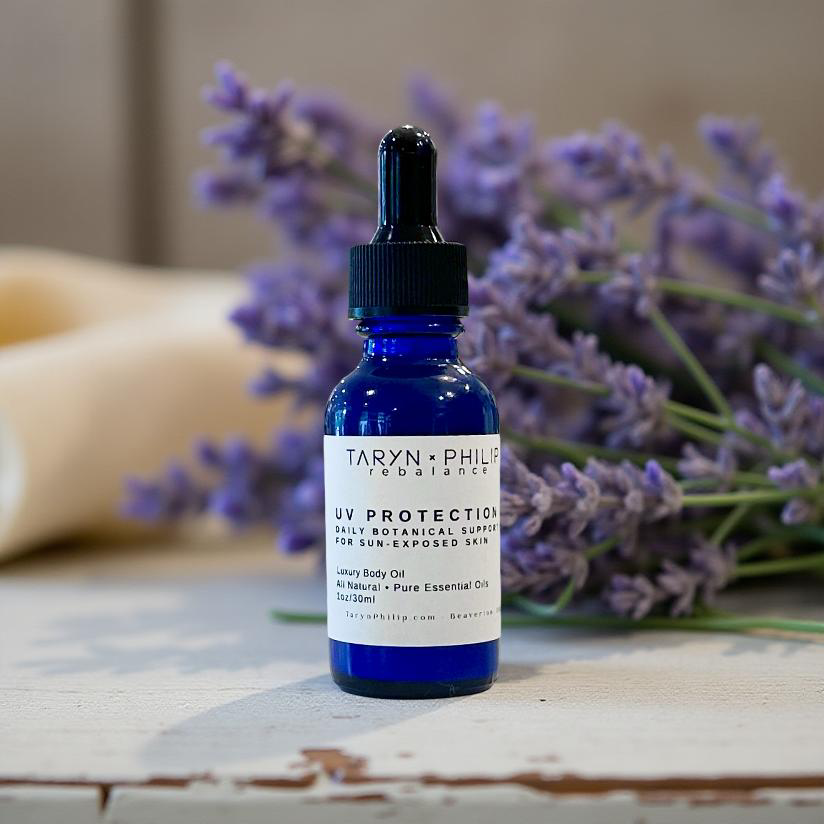Blue bottle with dropper labeled 'Taryn x Philip' on a wooden surface with lavender flowers in the background.