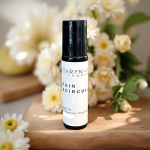 Taryn x Philip Pain & Circulation bottle on a wooden surface with flowers in the background