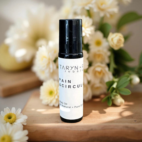 Taryn x Philip Pain & Circulation bottle on a wooden surface with flowers in the background