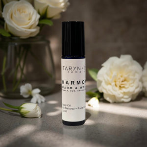 Taryn x Philip Harmony Warm & Wood body oil bottle with white flowers in the background