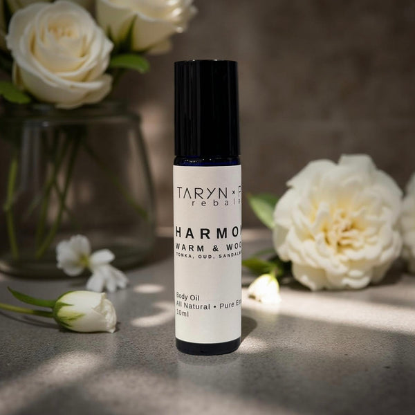 Taryn x Philip Harmony Warm & Wood body oil bottle with white flowers in the background