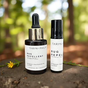 Two bottles of Taryn x Philip bug repellent on a natural background with a flower.